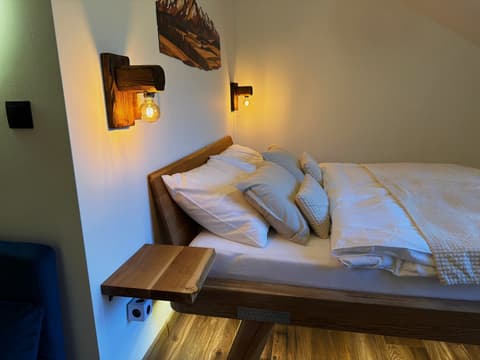 Double bed with wooden wall lamps under the wooden Tatra panorama