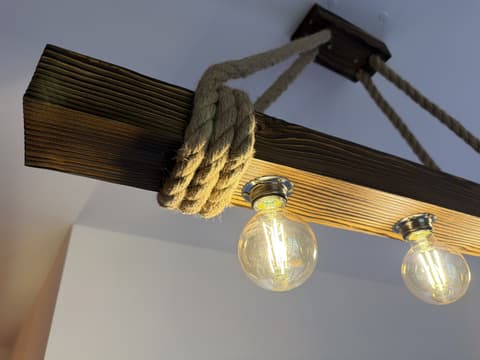 Lampa zo starého dreveného trámu zavesená na lanách s tromi retro žiarovkami