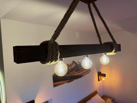 Lamp made of an old wooden beam hung on ropes with three filament bulbs