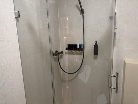 Sprchovací kút so sklenenými dverami, obkladom v štýle kameňa a čiernymi batériami