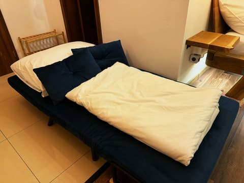 Blue sofa folded out into a bed with a pillow and a duvet