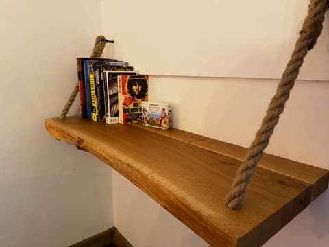 Live-edge oak shelf on ropes with books and Tatra playing cards