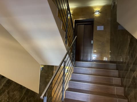 Schodisko s oceľovým zábradlím a dverami výťahu na medziposchodí