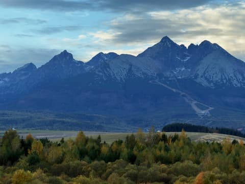 Lomnický štít and the neighbouring peaks above the autumn forest, photographed with zoom from the balcony