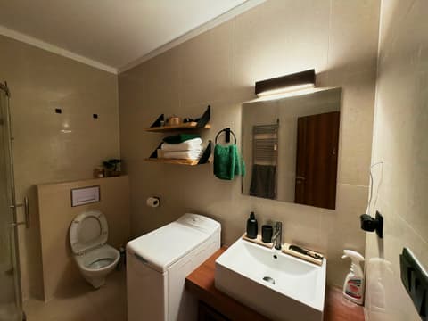 Bathroom with washbasin, washing machine, toilet, towel shelves and a heated towel rail