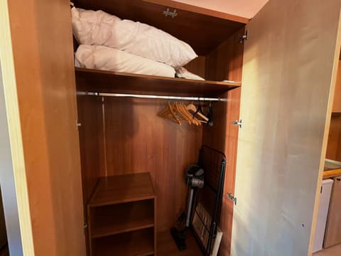 Wardrobe with spare pillows, hangers, a vacuum cleaner and a drying rack