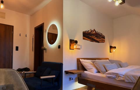 Blue fold-out sofa, backlit mirror and the double bed with wooden wall lamps