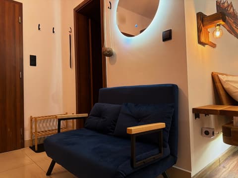 Entrance with coat hooks, a shoe rack, the bathroom door and the blue fold-out sofa