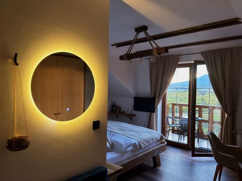 Backlit round mirror, beam lamp and the bed by the open balcony door with the Tatras outside