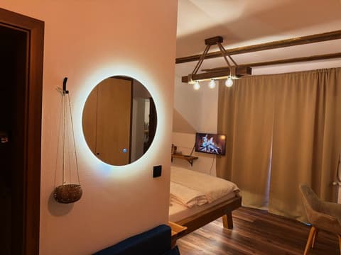 The round mirror lit in the evening, the beam lamp and the TV by the bed