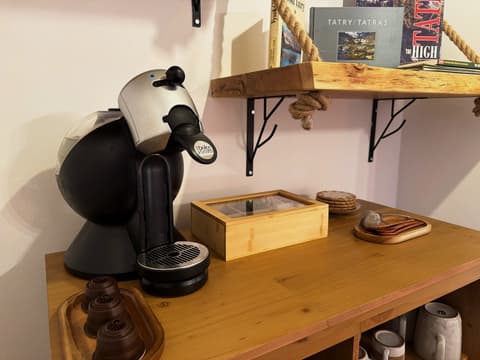 Capsule coffee machine, capsules, a tea box and cups on the sideboard