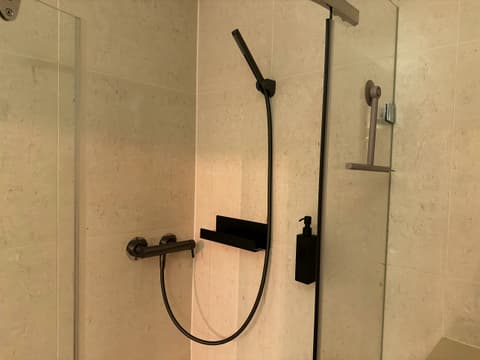 Shower with glass doors, stone-look tiles and black fittings